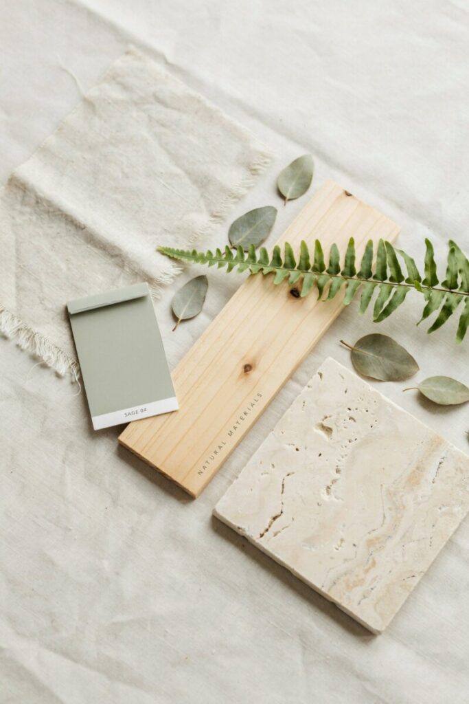 Natural materials for home interiors including linen, oak, travertine, and sage green paint used in biophilic design